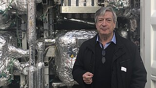 Dr Harry Lehmann stands in front of parts of a PtX plant in Werlte