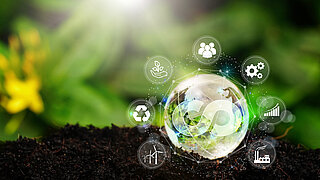 Kristallkugel mit einem Symbol für Kreislaufwirtschaft und umgeben von digitalen Icons, die verschiedene Aspekte der Nachhaltigkeit symbolisieren 