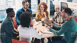 Sechs Personen sitzen um einen Tisch