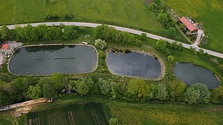 Blick von oben auf drei alte Klärteiche, daneben eine Straße und Grünflächen