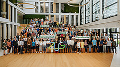 Mitarbeitende halten Schilder mit Aufschrift: Zukunft, Umwelt, Gesellschaft, Demokratie