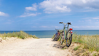 Ein Strandweg, im Hintergrund ist das Meer zu sehen, am Rand steht ein Fahrrad.