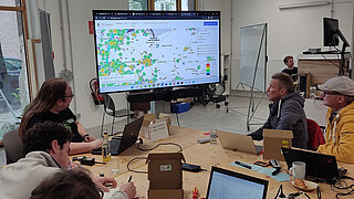 Teilnehmende des Workshops schauen auf eine digitale Karte