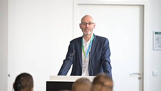 Ein Mann steht an einem Rednerpult. 
