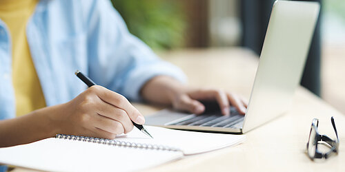 Person mit Stift am Laptop