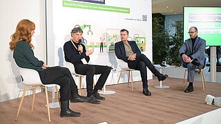 4 Personen sitzen auf einer Bühne und diskutieren