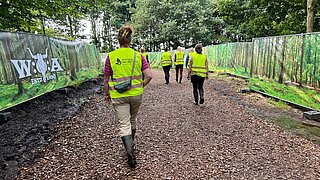 Mehrere Personen laufen über die Palludi-Matten (man sieht ihre Rücken), der Weg ist rechts und links eingezäunt