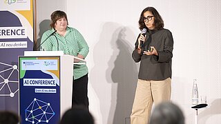 zwei Personen auf Podium mit Rednerpult