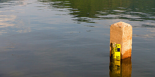 Hochwasser in einem Fluss mit Wasserstandsmesser