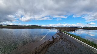 eine beschädigte und teilweise überflutete Straße, rechts und links davon Wasser