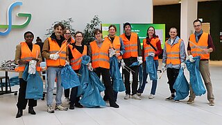 Eine Personengruppe mit Müllsäcken, Warnwesten, Handschuhen und Greifern posiert für die Kamera