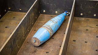Ein Stück alte Munition liegt in einer Kiste