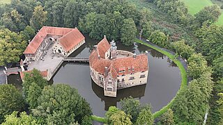 eine Burganlage, umgeben von einem Wassergraben im Wald 