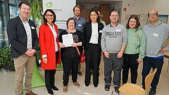 Mehrere Personen blicken in die Kamera. Eine hält eine Urkunde in der Hand. 