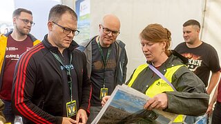 5 Personen schauen gemeinsam Bilder an. 