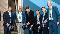 Mehrere Personen auf einer Bühne mit Gießkannen in der Hand