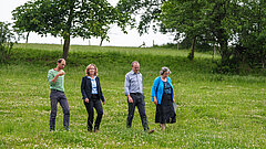 Steffi Lemke geht mit Projektmitarbeitenden über eine Wiese