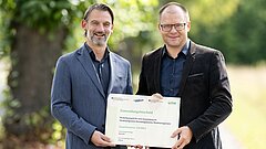 Bundesumweltminister Schneider und William Wolfgramm, Beigeordneter für Klima, Umwelt, Grün und Liegenschaften der Stadt Köln, halten Förderbescheid in den Händen
