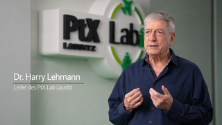 Ein Mann steht vor dem Logo des PtX Lab Lausitz und spricht