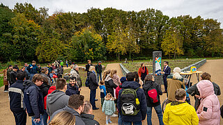 Viele Personen stehen vor einer Grünfläche