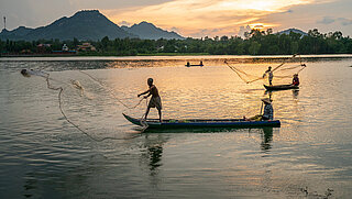 Fischer auf einem Boot werfen Netze ins Wasser 