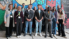Gruppenbild mit mehreren Personen vor einer bunten Wand