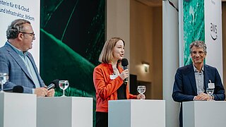 drei Personen stehen auf einer Bühne