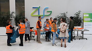 Mehrere Personen stehen vor einem Tisch und holen sich Materialien zum Müllsammeln