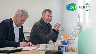 Oberbürgermeister und ein weiterer Mann hören zu und machen Notizen