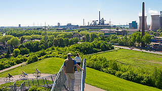 Panoramasicht auf ein Industriegebiet mit Radfahrenden und Fußgänger*innen