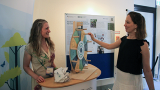 Zwei Frauen stehen vor einem Glücksrad am Stand der Internationalen Klimaschutzinitiative.