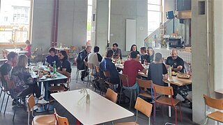 Eine Gruppe Teilnehmender sitzt in einer Kantine zum Mittagessen