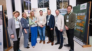 Mehrere Personen stehen nebeneinander und blicken in Richtung Kamera. Neben ihnen stehen Rollups. 