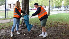 Zwei Personen sammeln Müll. 