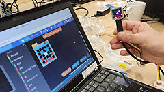 ein Laptop, daneben hält eine Hand einen Sensor 