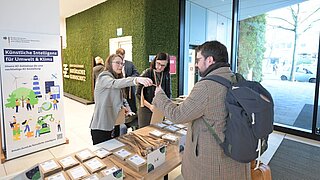 Eine Person steht vor einem Registrierungstisch und erhält ihr Namensschild von einer anderen Person