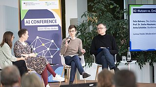 Vier Personen auf einem Podium mit Roll-ups im Hintergrund