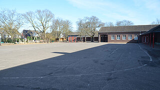 Asphaltierter Schulhof und Gebäude der Adam-Riese-Schule in Meerbusch