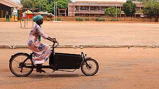 Eine schwarz-afrikanische Frau Fährt auf einem Lastenfahrrad