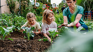 Frau mit zwei Kindern im Garten