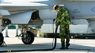 Ein Soldat betankt ein Militärflugzeug.