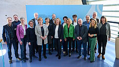 Steffi Lemke und weitere Personen posieren gemeinsam vor einer blauen Wand