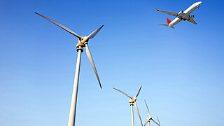 Ein Flugzeug fliegt über Windkraftanlagen.