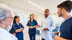 Several people in medical attire are standing in a room and talking to each other