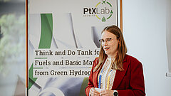 A woman is standing in front of a poster in a room.