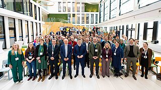 Ein Gruppenbild mit vielen Personen, unter anderem Bundesminister Carsten Schneider, im Atrium des ZUG-Gebäudes