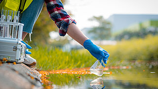 Person nimmt Wasserprobe aus Gewässer
