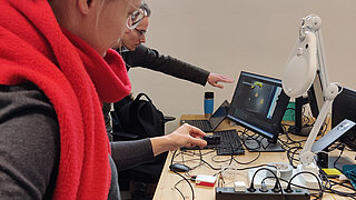 Zwei Personen vor technischem Versuchsaufbau