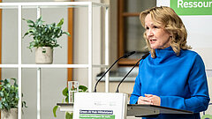 Eine Frau steht an einem Rednerpult. 