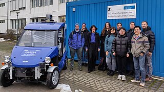 Mehrere Personen stehen neben einem Elektrofahrzeug